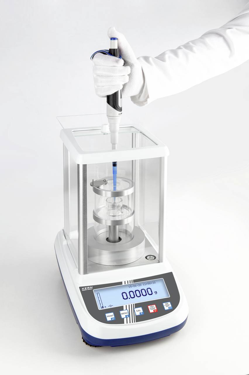 Une personne remplit un récipient avec un liquide à l'aide d'une pipette sur une balance numérique de laboratoire.