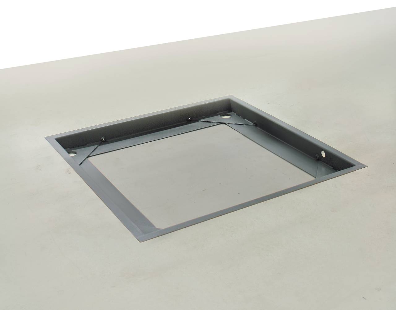 Une cavité rectangulaire dans une surface grise, probablement destinée à recevoir un objet ou un couvercle.