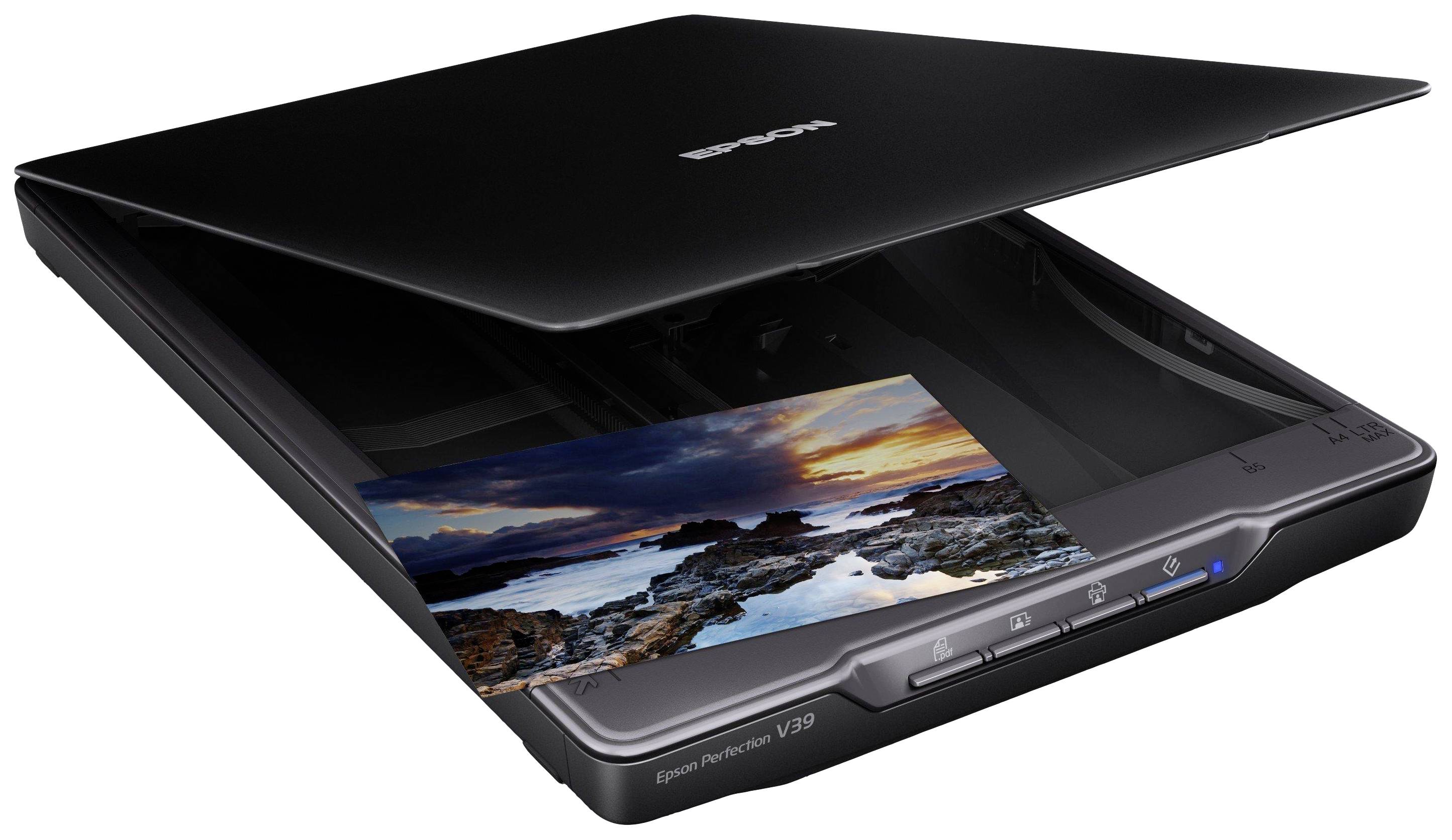 Un scanner plat numérise une photo d'un paysage côtier au coucher de soleil. Le couvercle du scanner est légèrement ouvert.