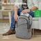 Un homme est assis sur un canapé et emballe un sac à dos gris pour ordinateur portable, adapté aux ordinateurs portables de 16 pouces.