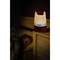 Une lampe de camping lumineuse est posée sur une table de chevet à côté d'un enfant endormi dans une chambre sombre.