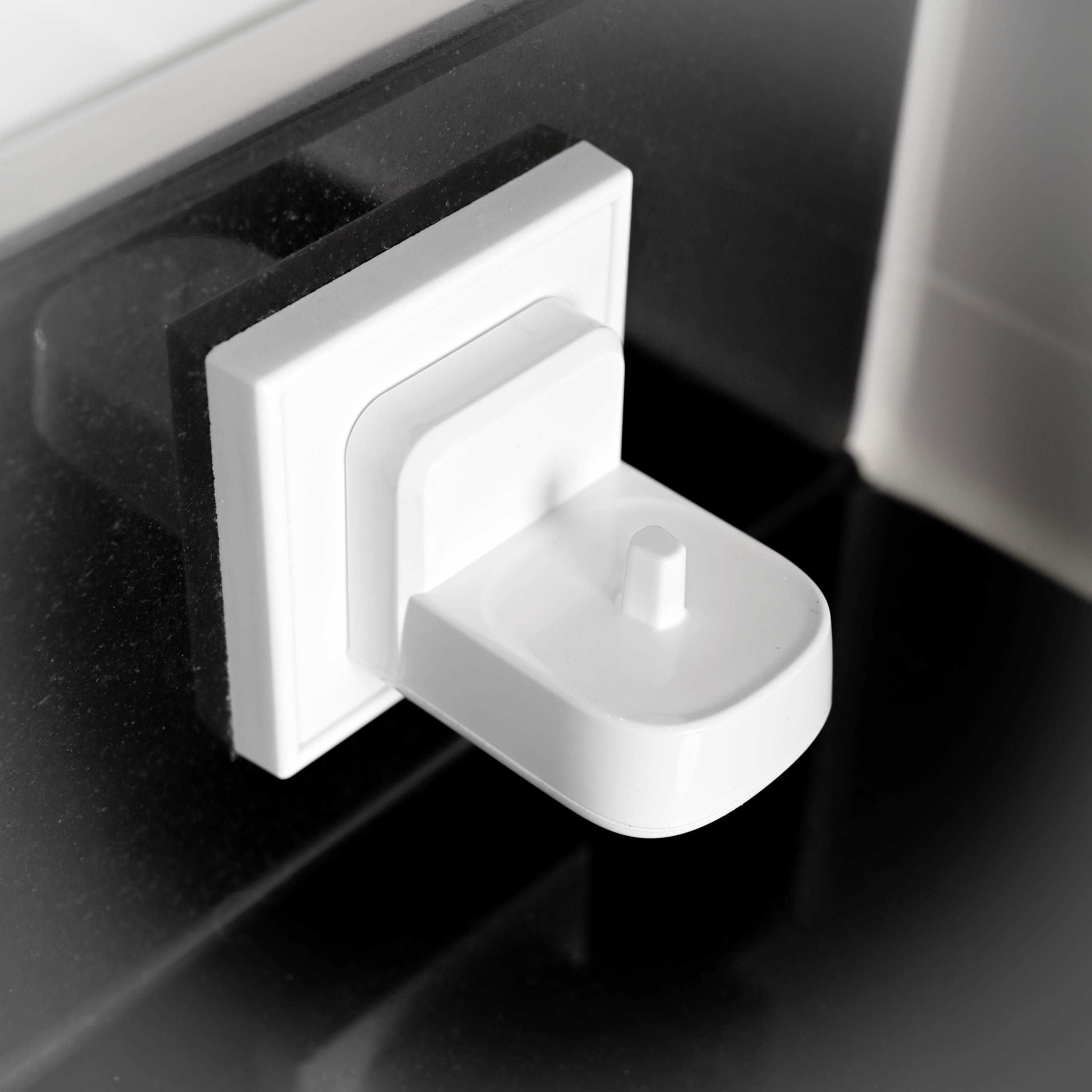 Prise électrique blanche sur un mur noir, au design moderne et minimaliste.