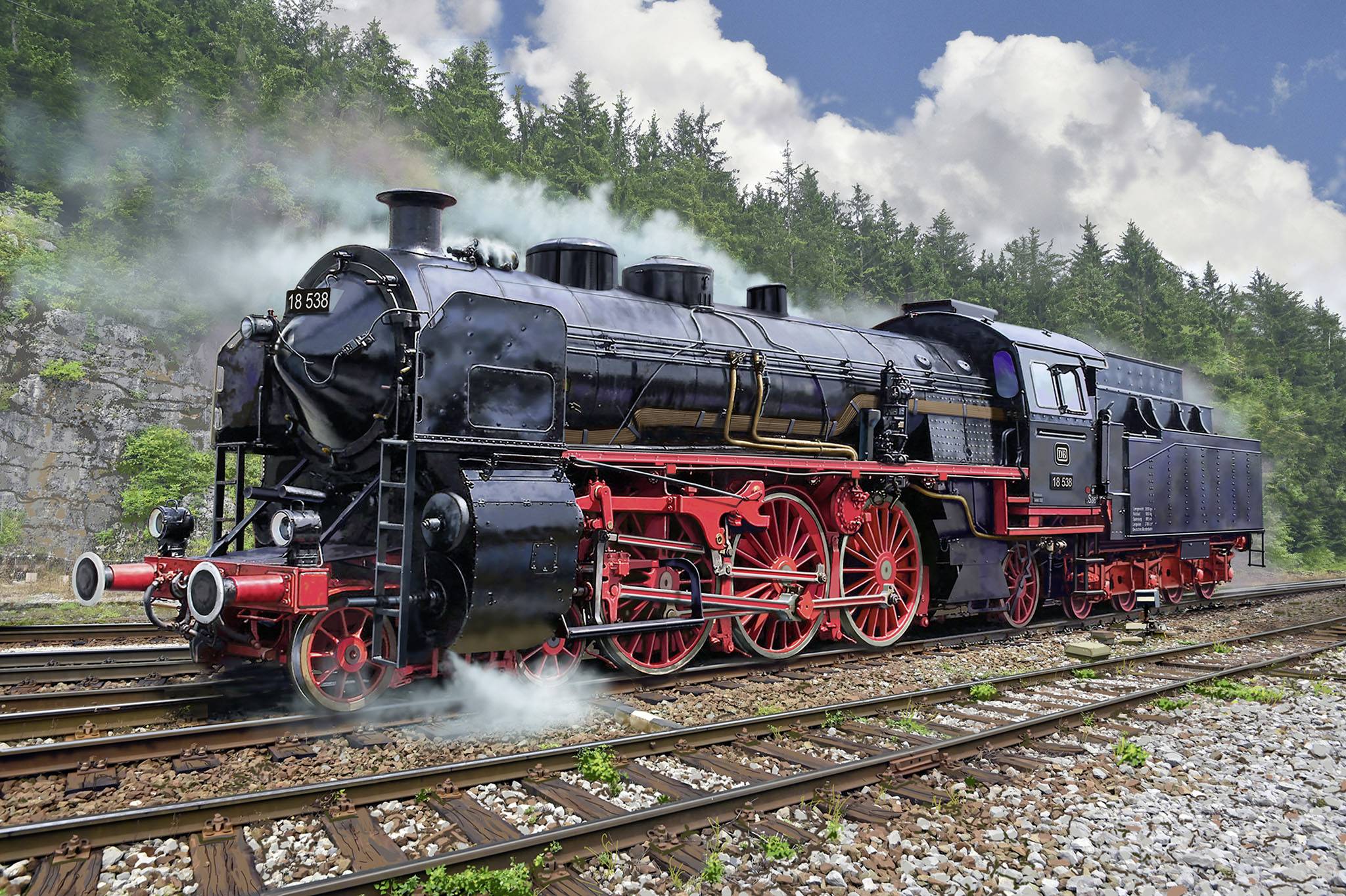 Ancienne locomotive à vapeur sur des rails, entourée de collines boisées et d'un ciel bleu parsemé de nuages. La fumée s'échappe de sa cheminée.