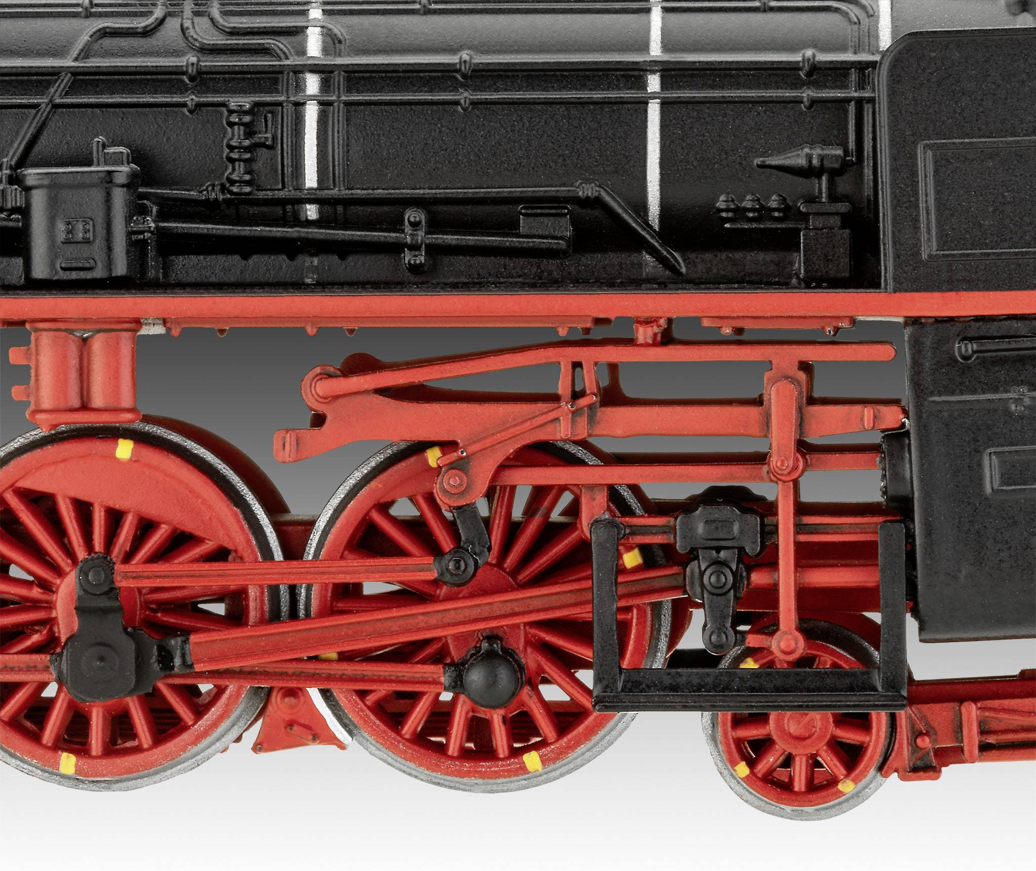 Gros plan d'un châssis de locomotive à vapeur historique avec des roues en métal rouge et noir et des bielles visibles.