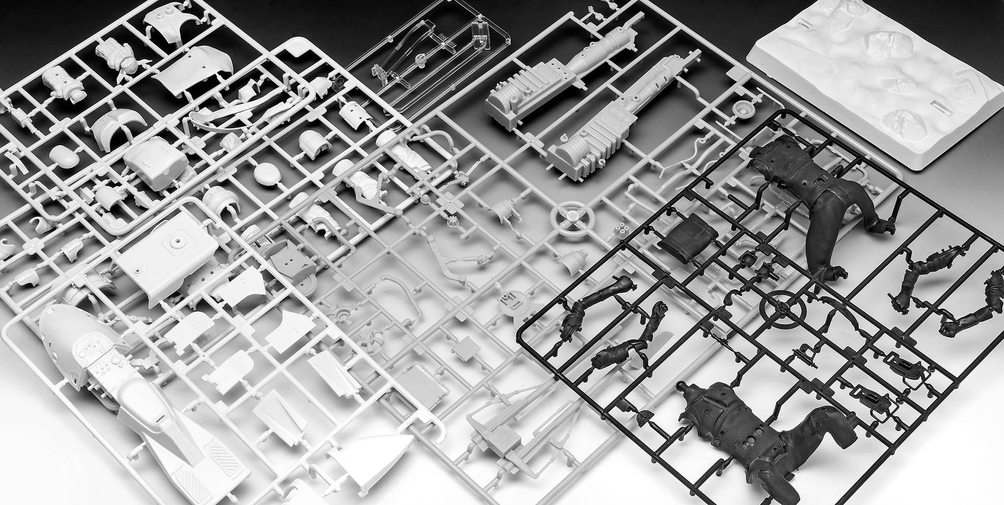 Kit de construction d'un véhicule militaire avec des pièces détaillées en plastique sur support de moulage. Les pièces comprennent des armes, des roues et une coque.