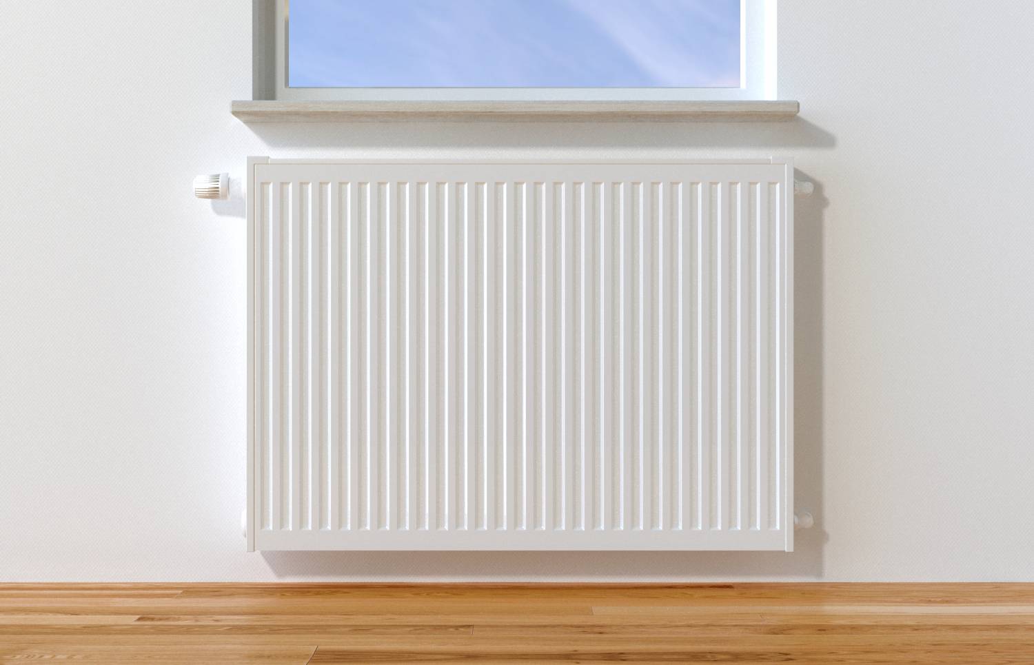 Un radiateur blanc sur un mur en dessous d'une fenêtre à travers laquelle on voit un ciel bleu. Un sol en bois en dessous.