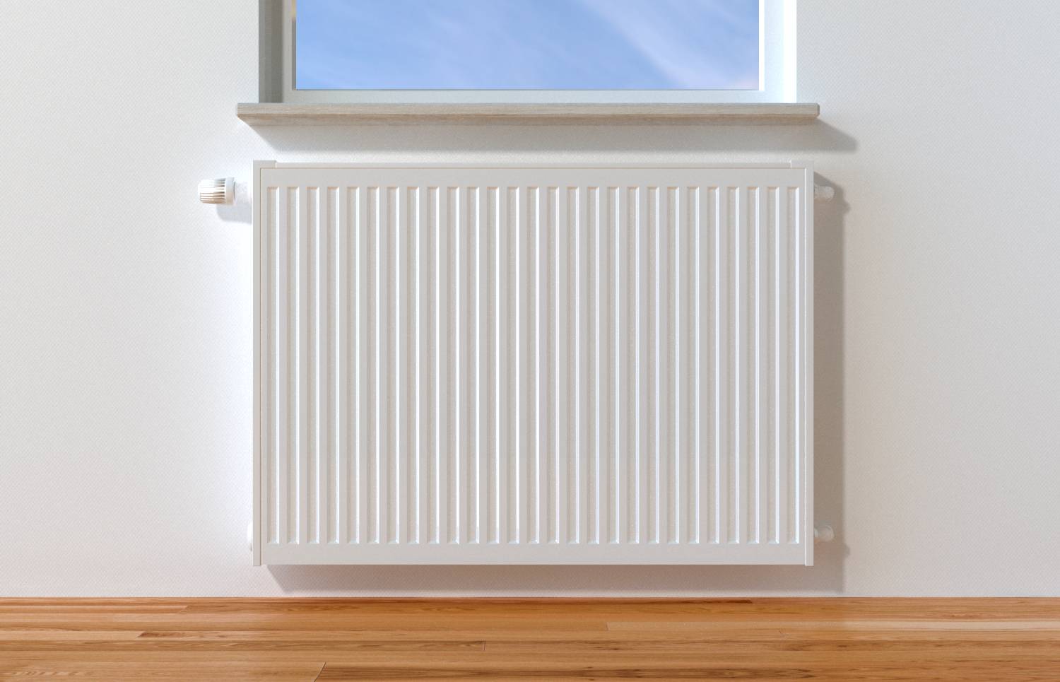 Radiateur blanc monté au mur sous une fenêtre dans une pièce simple avec un sol en bois clair.