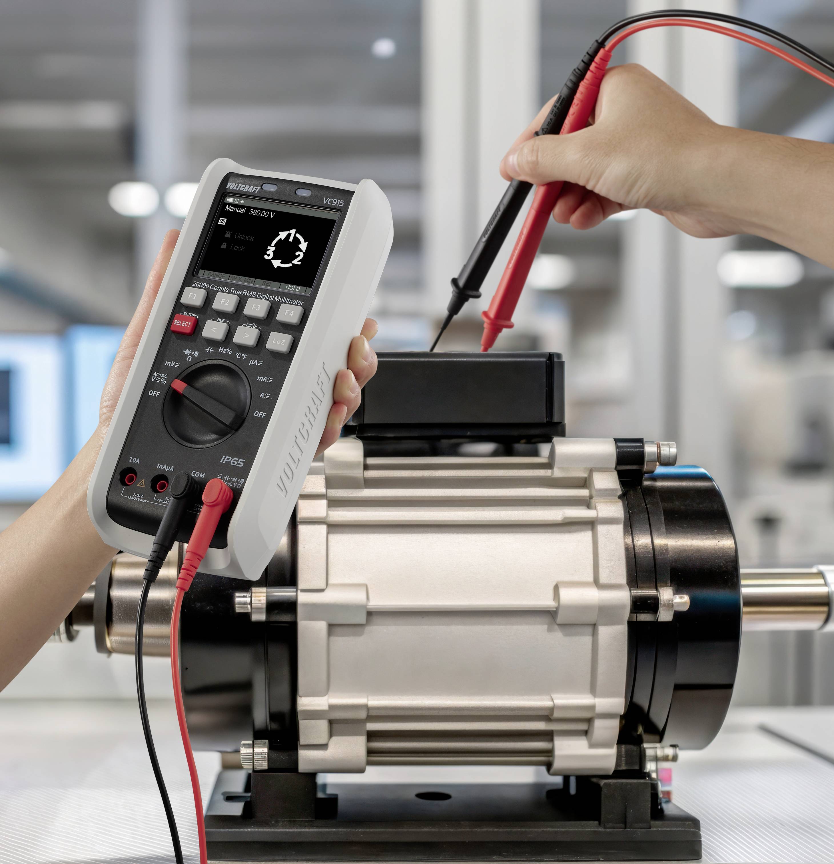 Une personne utilise un multimètre pour mesurer les valeurs électriques sur un moteur industriel dans un environnement de laboratoire.