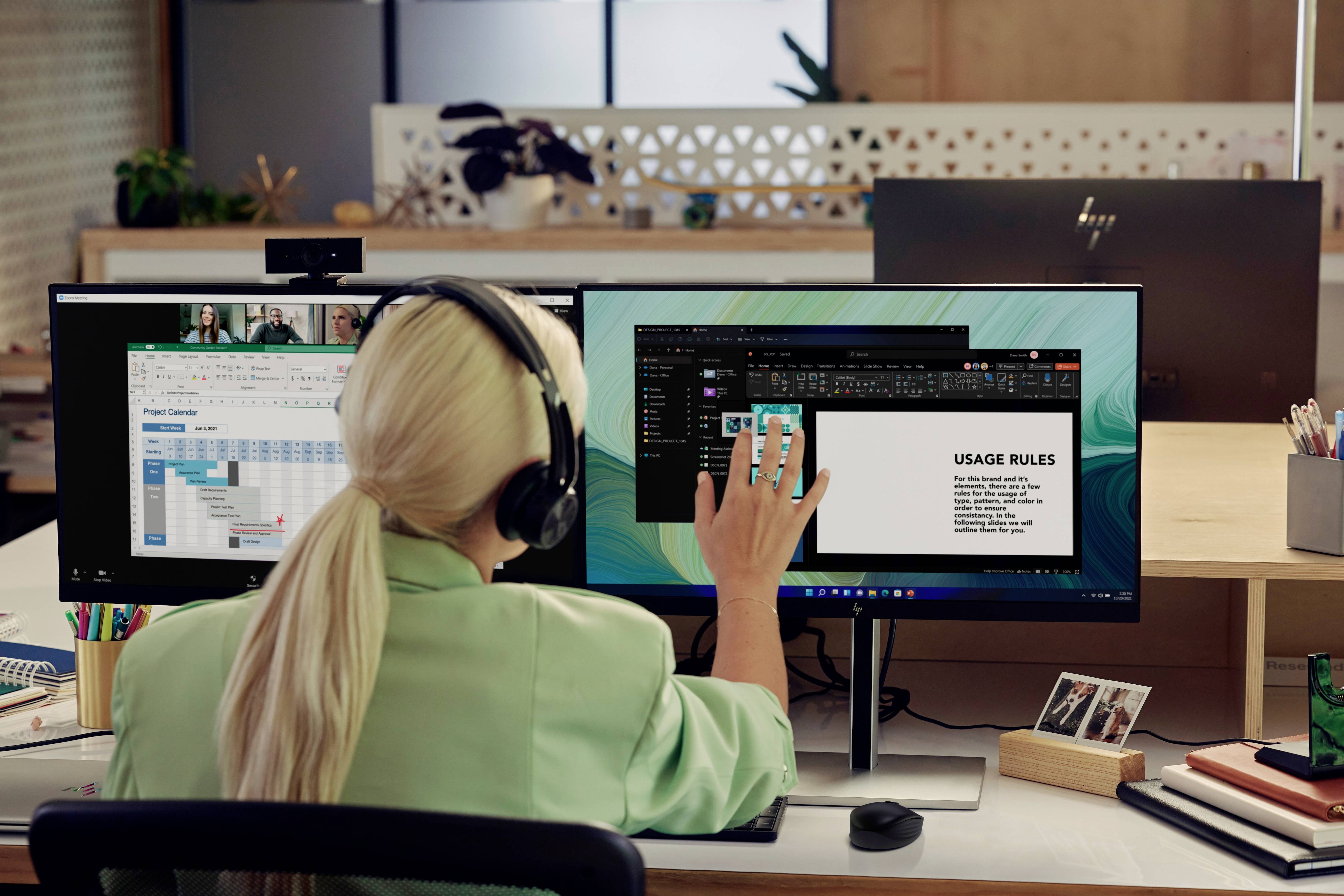 Une femme est assise à son bureau avec des écouteurs, travaillant sur deux écrans ; à gauche un tableur, à droite une présentation avec 'RÈGLES D'UTILISATION'.