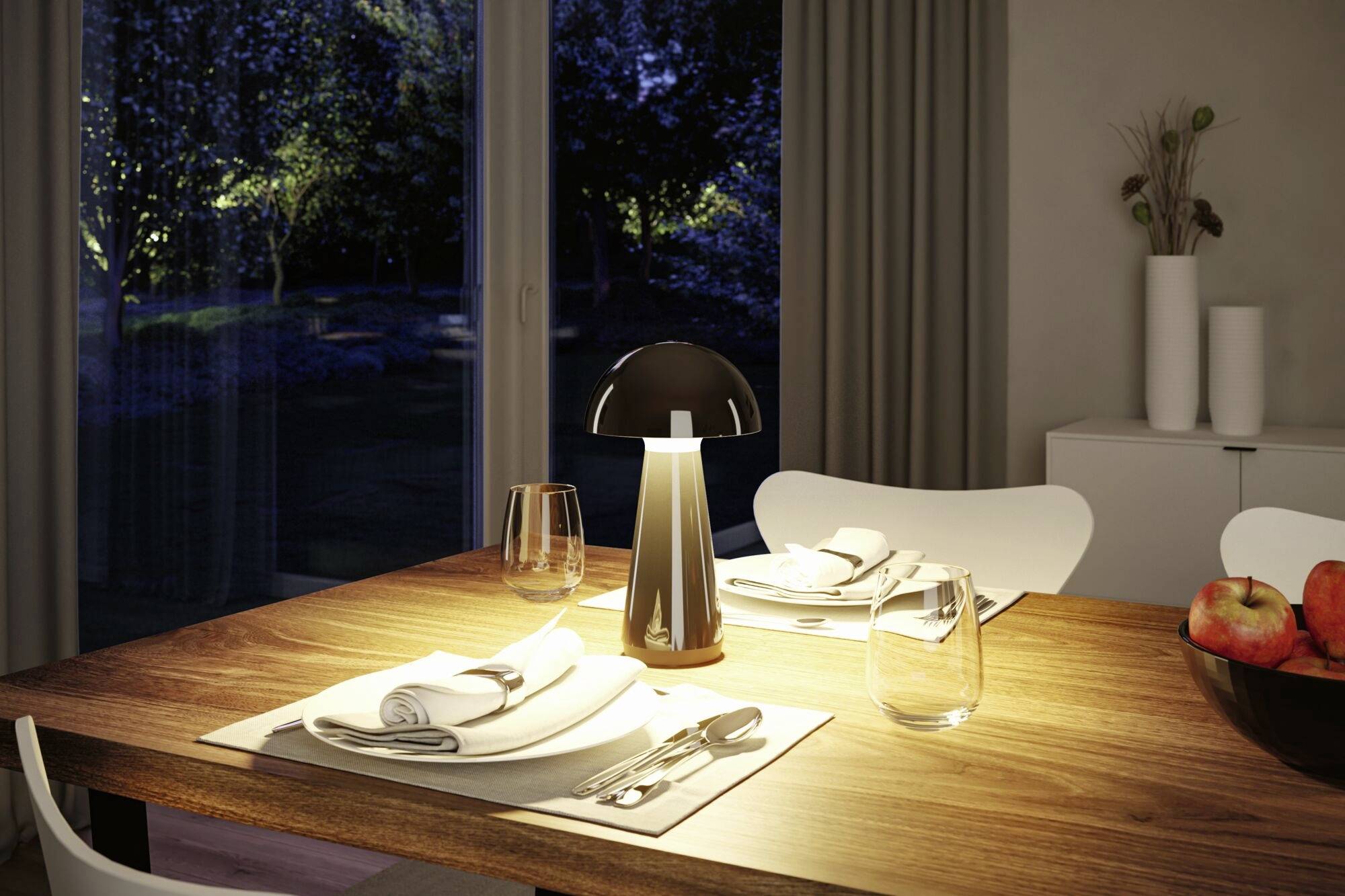 Une table joliment dressée de nuit, éclairée par une petite lampe. Un jardin est visible à travers la fenêtre.