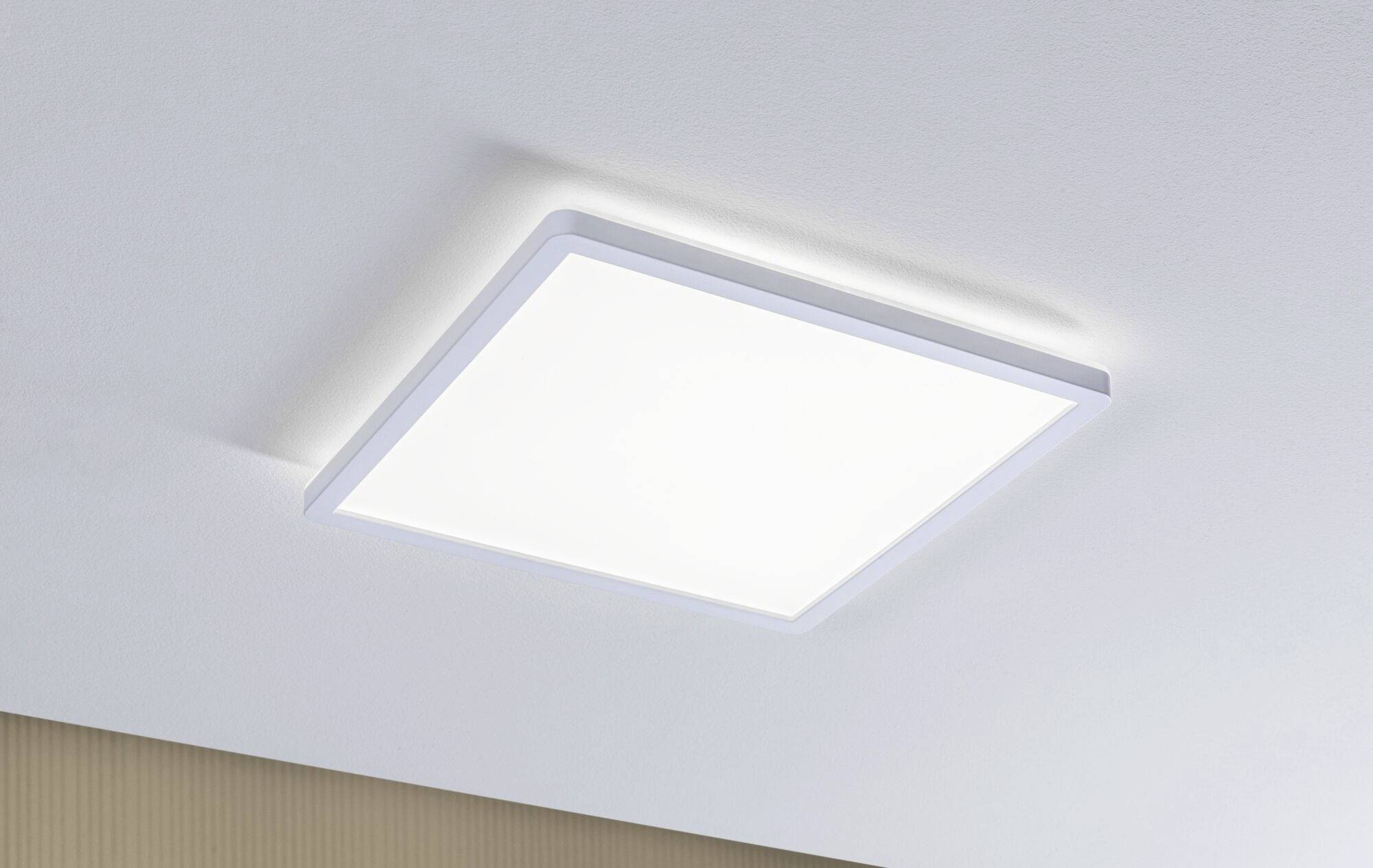 Une lampe de plafond carrée éclaire intensément une pièce aux murs blancs, ce qui suggère un aménagement moderne et minimaliste.
