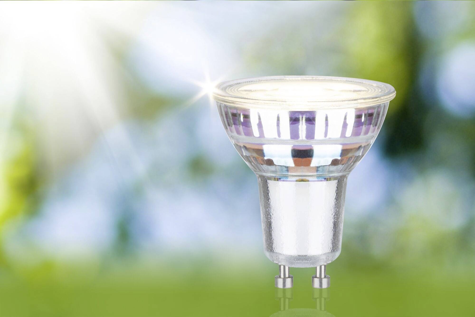 Une lampe LED devant un arrière-plan vert flou, sur lequel le soleil brille.