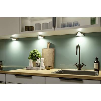Cuisine moderne avec un crédence bleu clair et un plan de travail en bois. Des éclairages intégrés illuminent l'étagère avec de la vaisselle, une planche à découper et un pot de basilic à côté de l'évier.