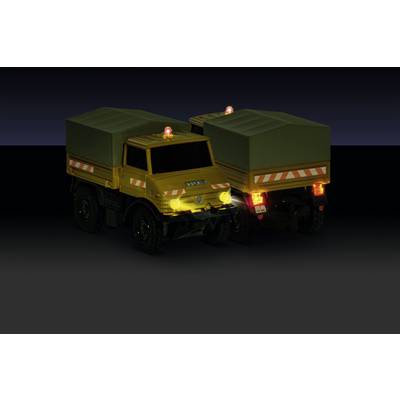 Deux camions-jouets jaunes avec des feux oranges et des bâches vertes sont disposés sur un fond sombre. Ils sont visibles de l'arrière et de l'avant.
