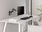 Un bureau moderne avec un bras de support de moniteur fixé au mur, sur lequel un écran est suspendu. Le clavier et la souris sont posés sur le bureau.