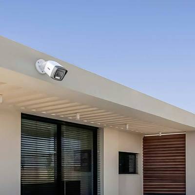 Une caméra de sécurité est installée à l'extérieur d'un bâtiment moderne sous un ciel bleu.