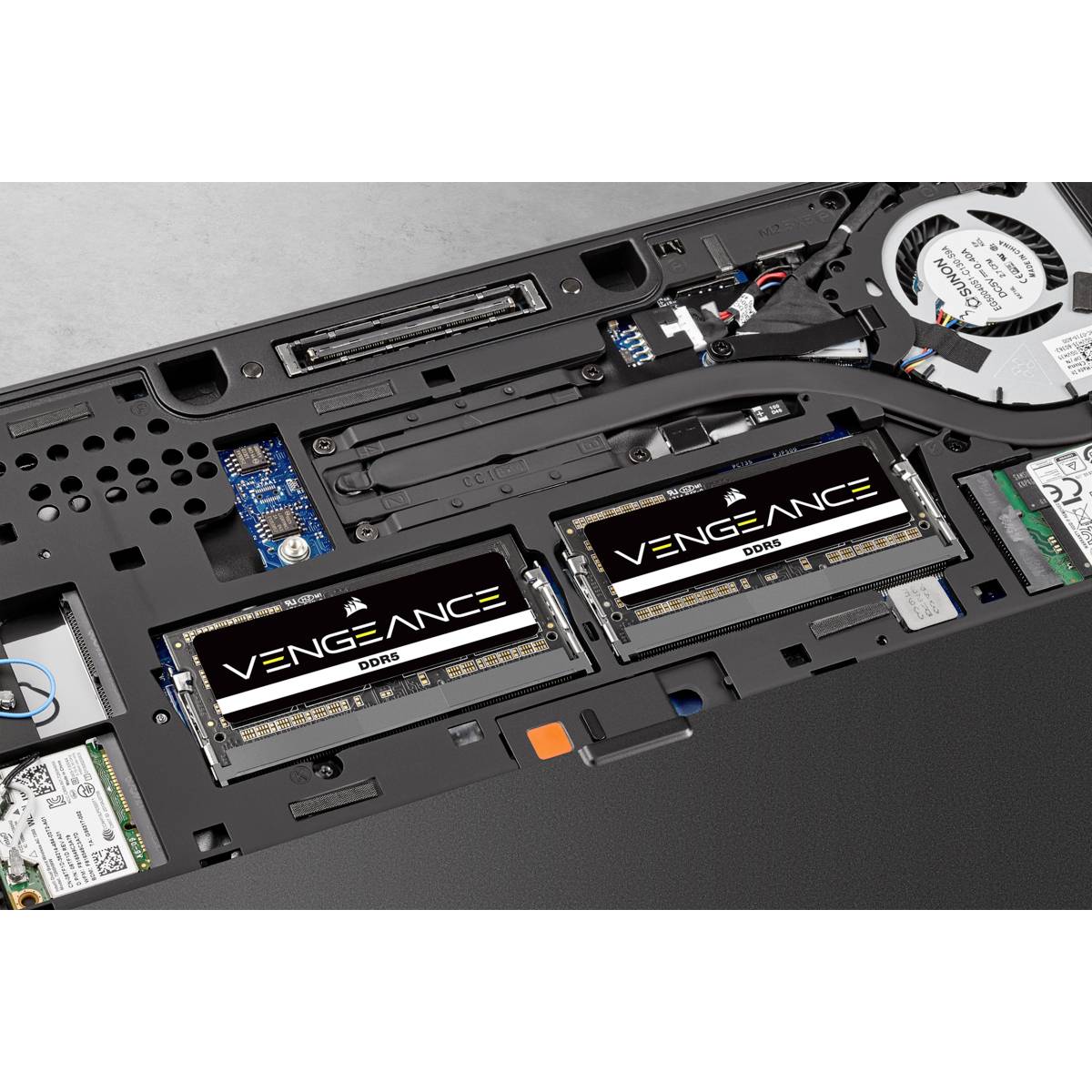 Un ordinateur portable ouvert révèle deux modules de RAM DDR5 Corsair Vengeance à l'intérieur, entourés d'autres composants internes.