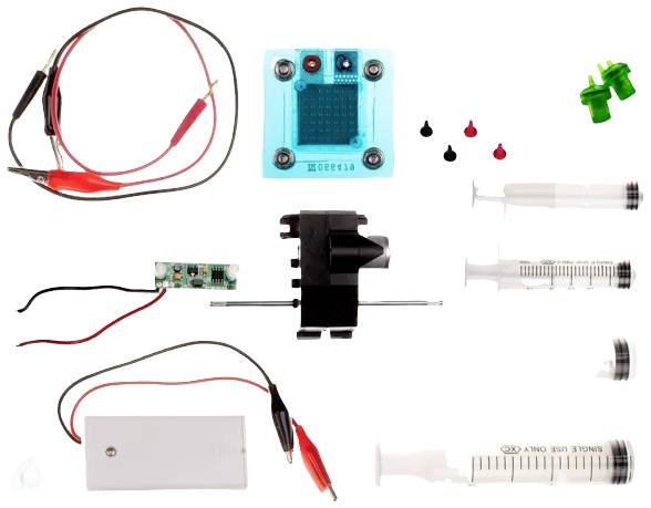 Kit de composants électroniques, seringues et câbles pour la réalisation d'expériences scientifiques sur surface de table.