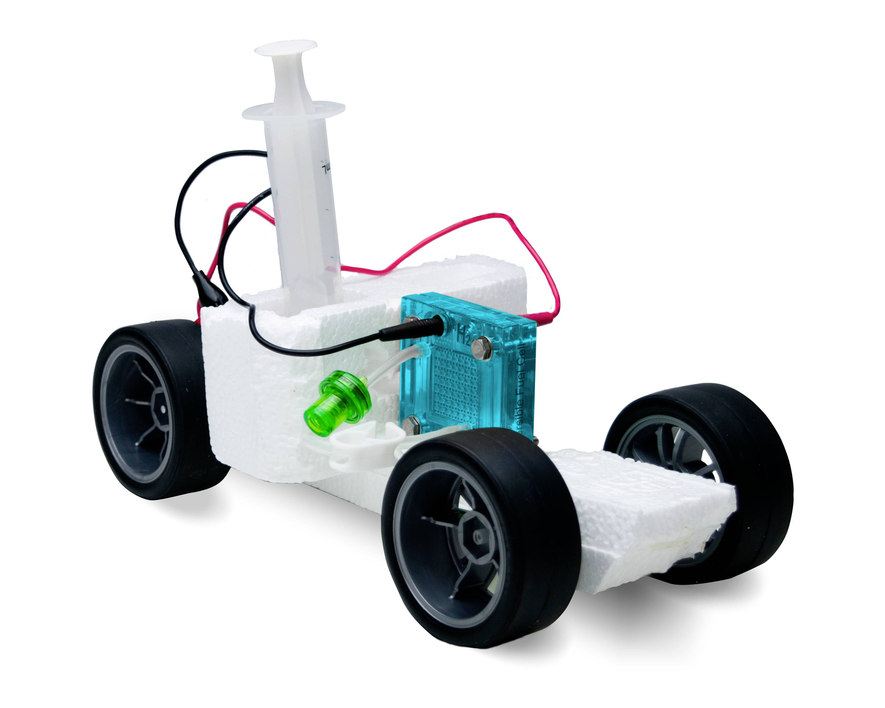 Une voiture miniature en polystyrène avec quatre roues, une seringue comme moteur, des câbles rouges et une lampe LED verte, symbolise une technologie durable.