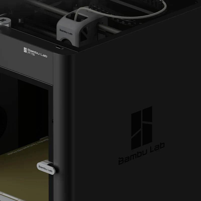 Un imprimante 3D moderne de la marque 'Bambu Lab' de couleur gris foncé, avec un espace d'impression ouvert et des pièces mécaniques visibles.
