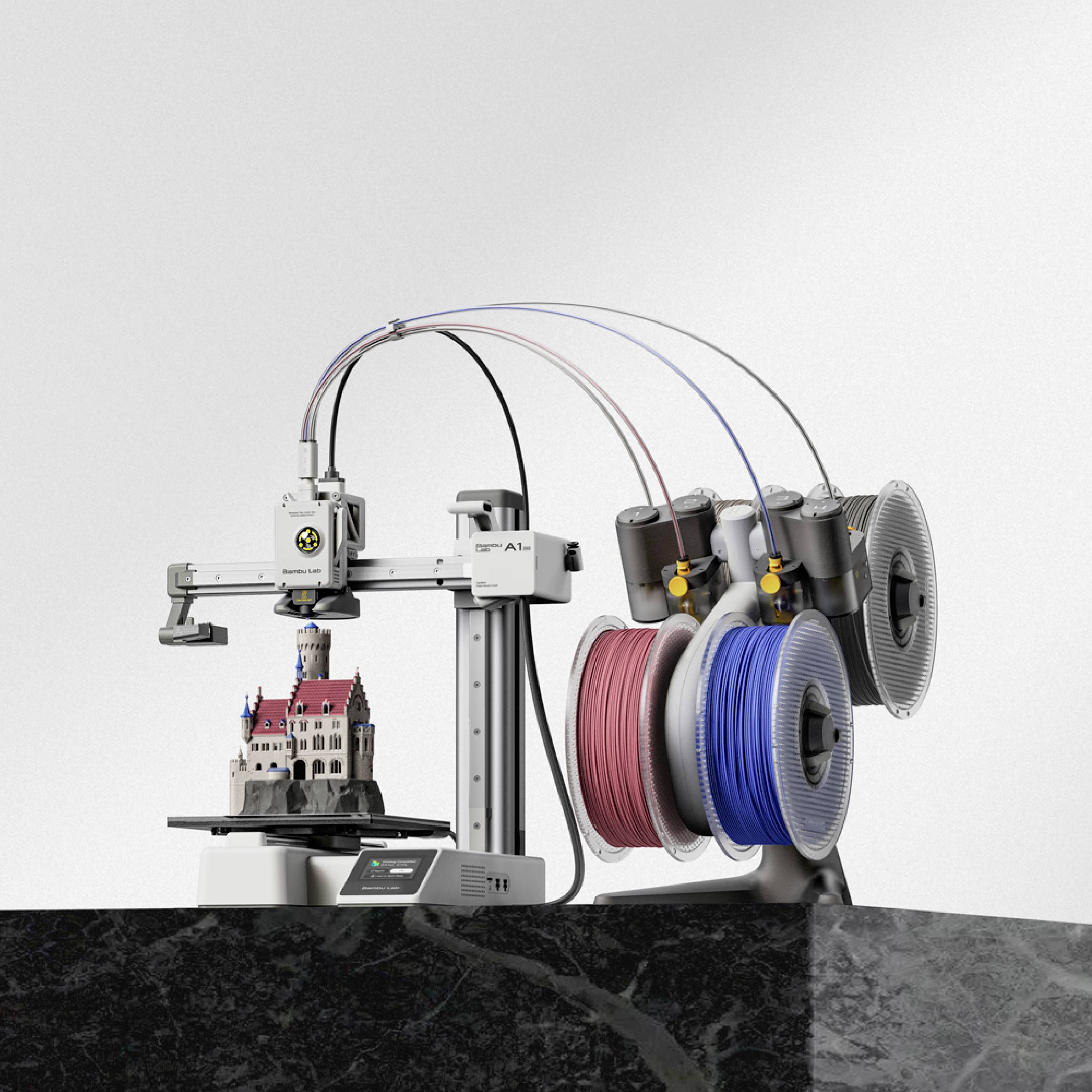 Une imprimante 3D crée un modèle détaillé d'un château. À côté se trouvent des bobines de filament de différentes couleurs.