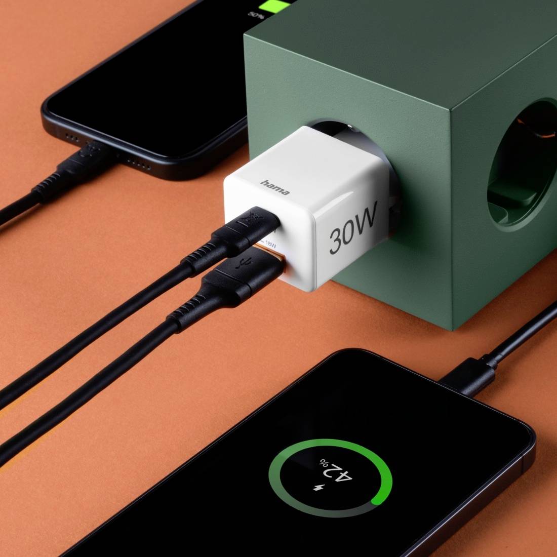 Plusieurs smartphones sont en train de se charger avec un chargeur de 30W. Un cube vert avec des câbles relie les appareils.