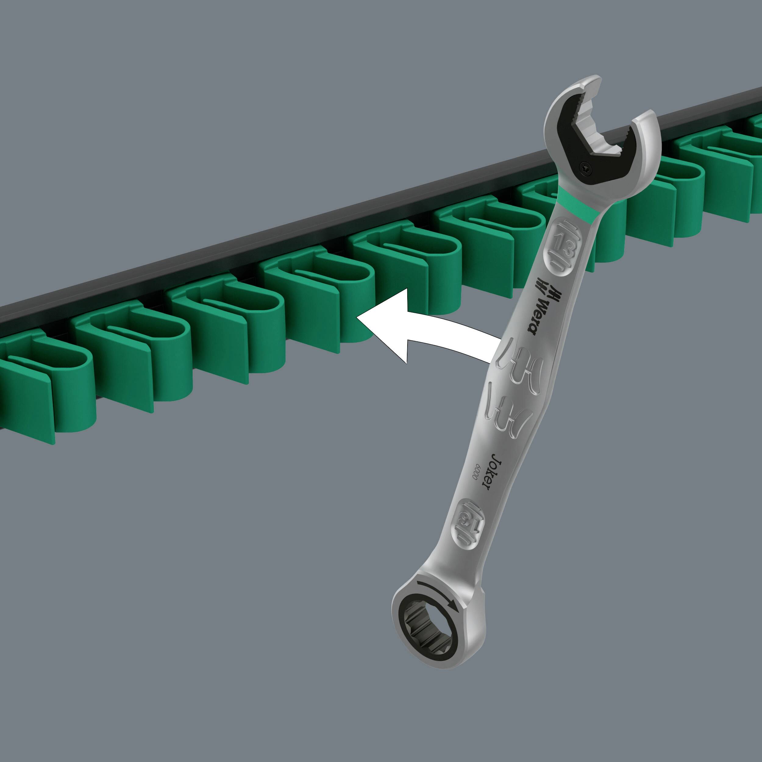 Une clé à molette est retirée d'un support à outils vert. Le support comporte plusieurs emplacements pour différents outils.