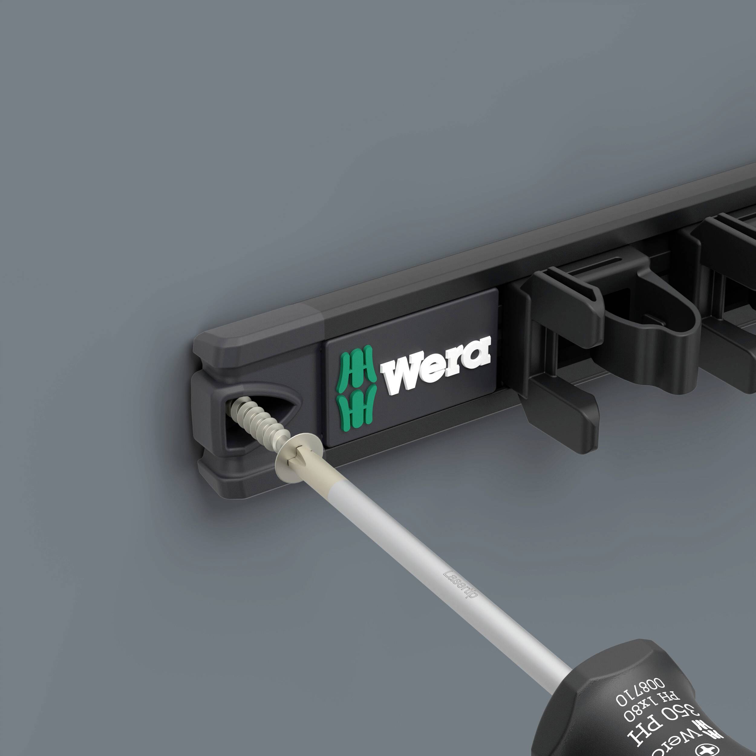 Un tournevis est placé dans un support mural noir de Wera. Le support dispose d'emplacements pour plusieurs outils.