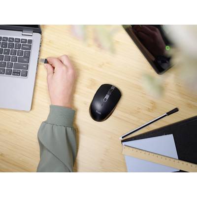 Une personne insère une clé USB dans un ordinateur portable posé sur une table avec une souris sans fil, une tablette, un stylo et un carnet de notes.