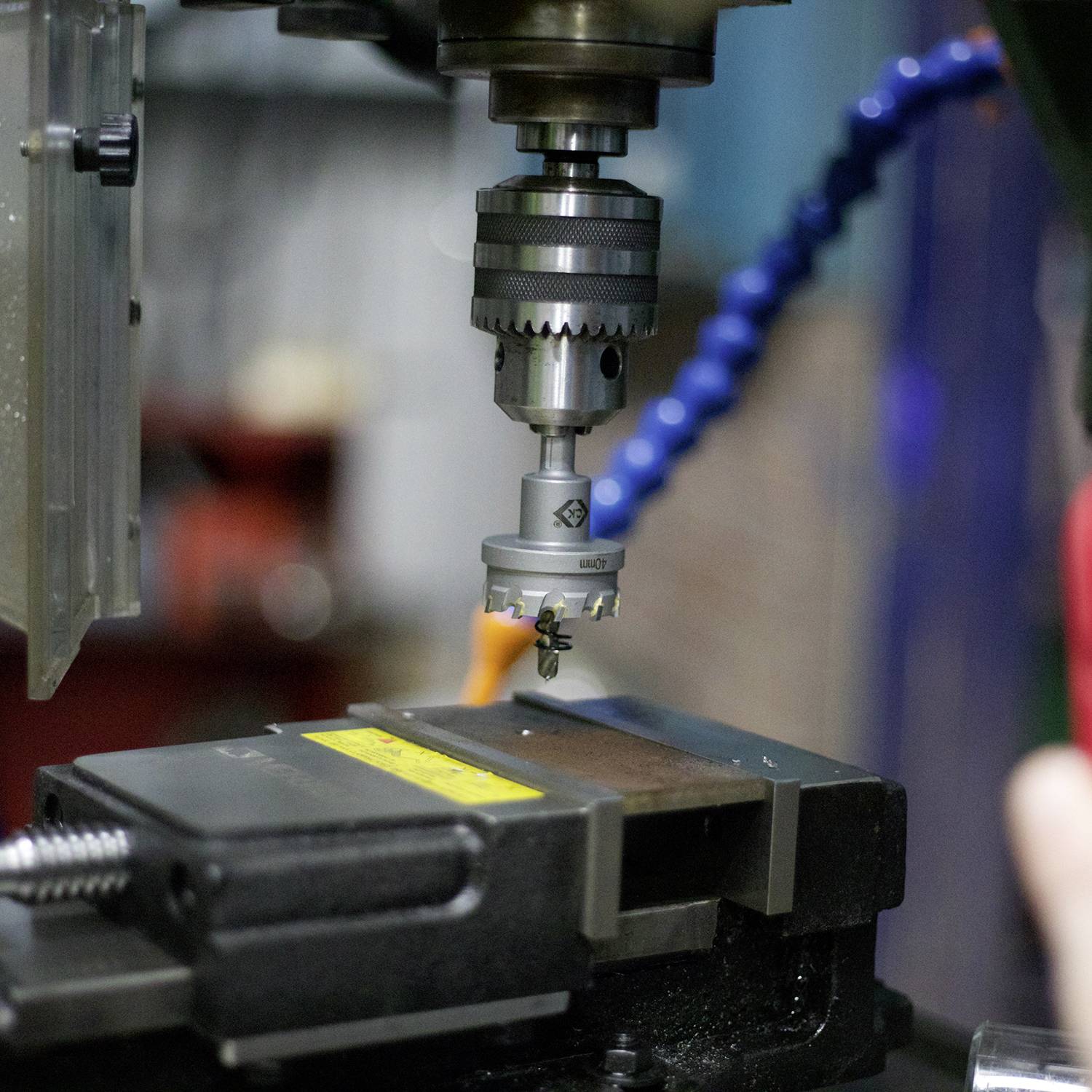 Une fraiseuse CNC usiné une pièce métallique, la tête de fraisage en action. Des machines floues sont visibles en arrière-plan.