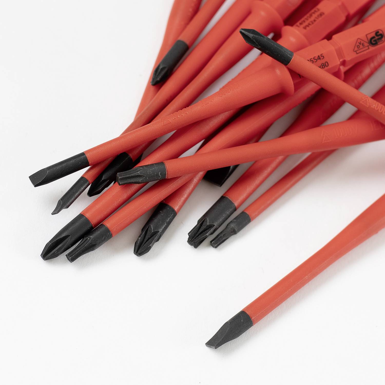 Un ensemble de tournevis rouges avec des embouts noirs sur une surface blanche, tous munis de poignées coudées.