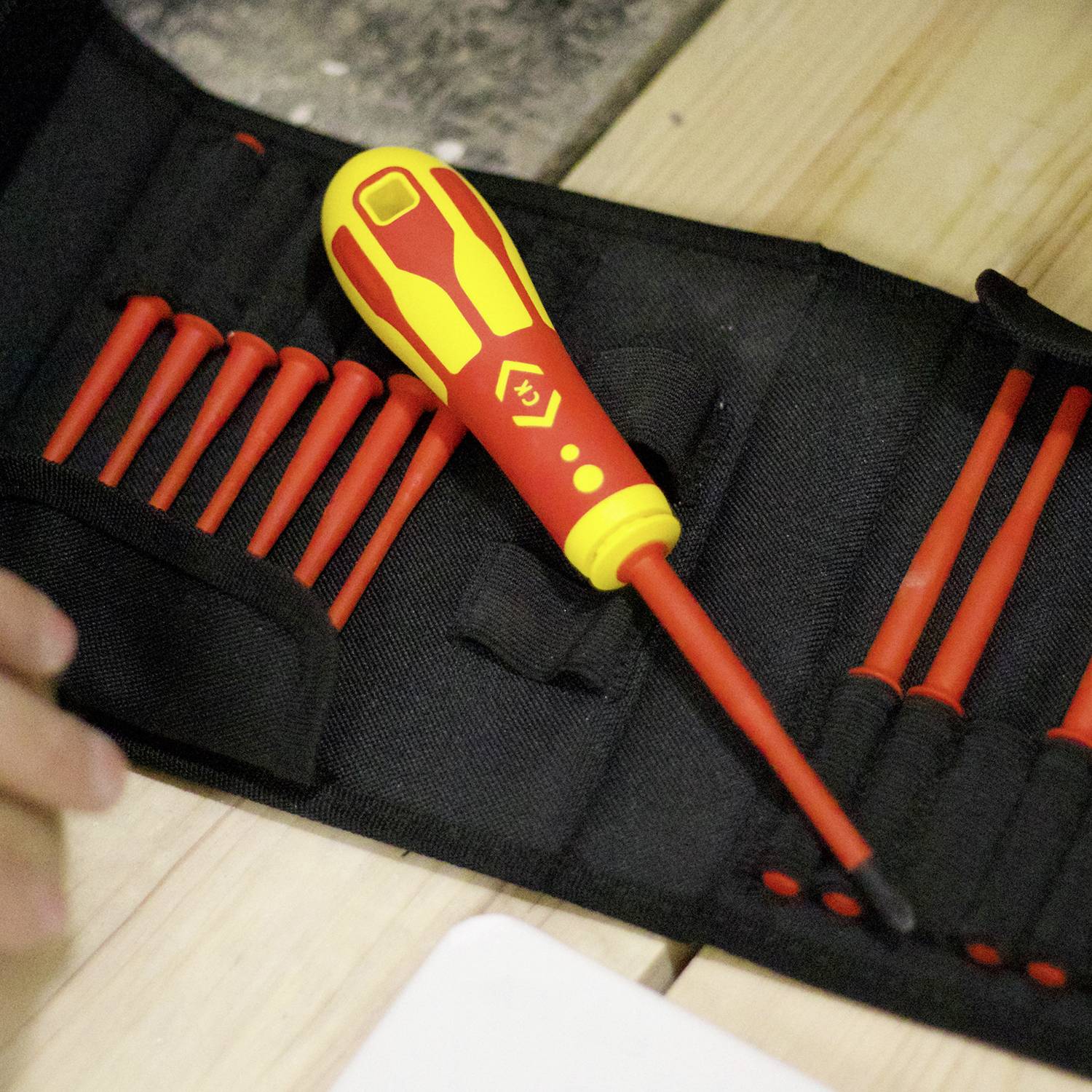 Un ensemble de tournevis isolés dans un sac, posé sur une table en bois.