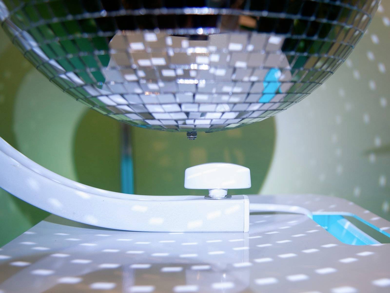 Une boule disco réfléchissante projette des points lumineux sur un mur. Les réflexions lumineuses créent une atmosphère dynamique.