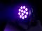 Un projecteur LED émet une lumière violette dans une pièce sombre. Le projecteur possède des lentilles rondes disposées en motif de grille.
