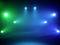 Une scène avec un éclairage coloré en bleu et vert, rayonnant dans différentes directions, crée une atmosphère empreinte d'émotion.
