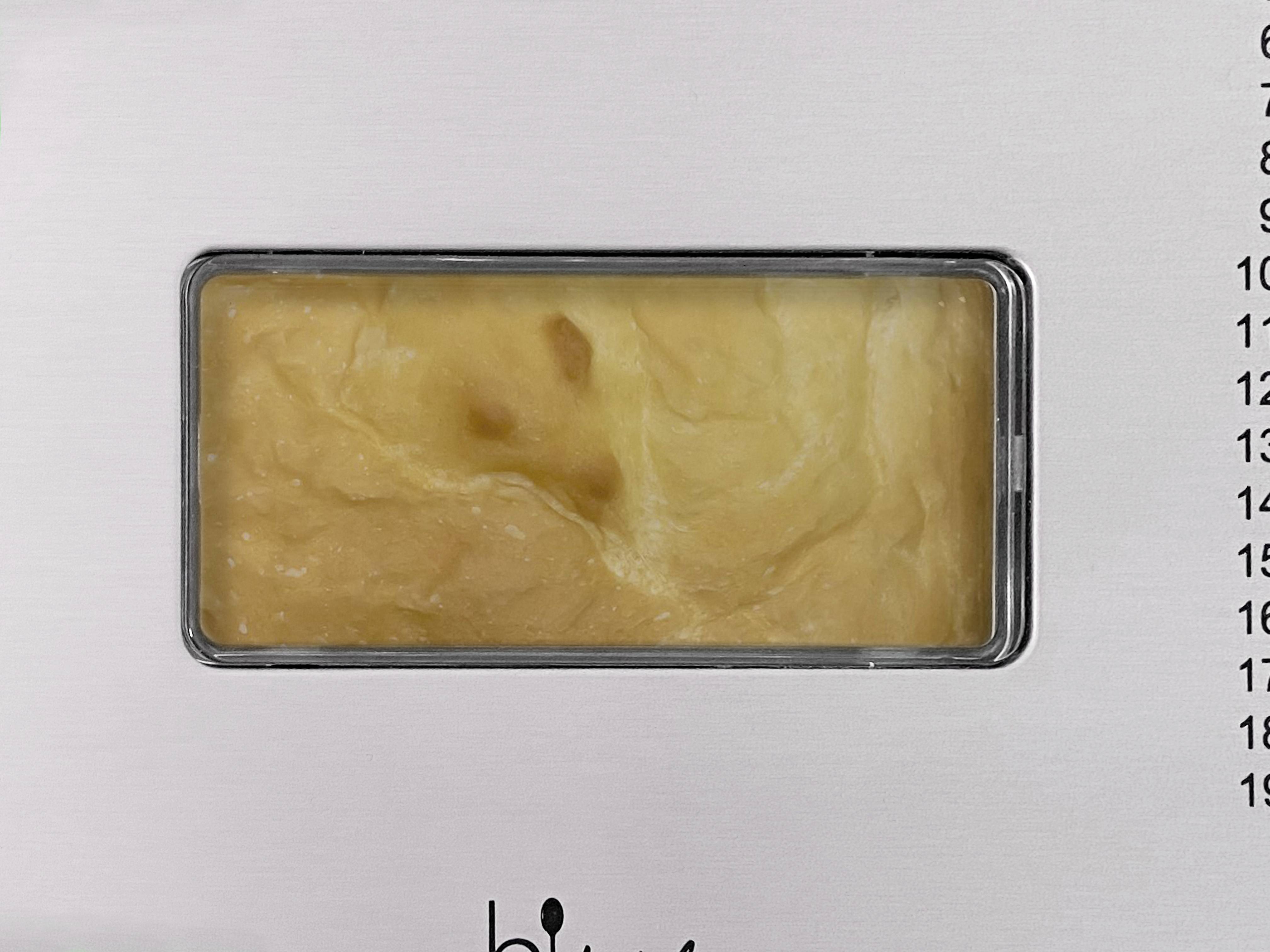 Processus de brassage visible à travers le hublot d'une machine, la masse de pâte se remue.