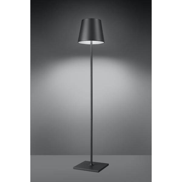 Lampadaire avec un abat-jour gris moderne, illuminant une pièce sombre, projetant une lumière uniforme sur le mur, minimaliste et élégant.