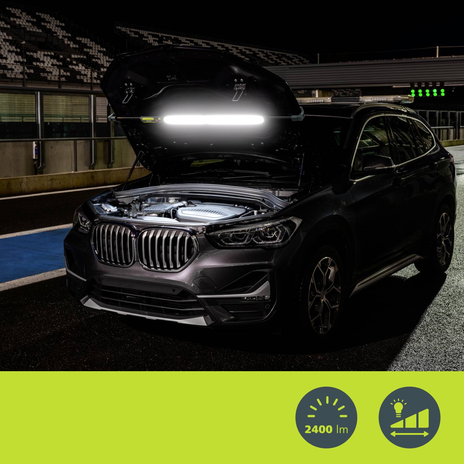 Voiture avec capot ouvert sur une piste sombre, compartiment moteur éclairé par une lampe d'atelier à forte luminosité de 2400 lumens.