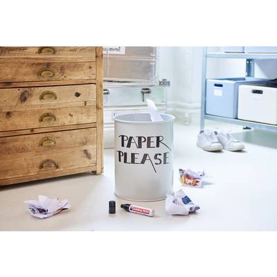 Une poubelle portant l'inscription 'Paper Please', entourée de papiers froissés et de fournitures de bureau au sol.