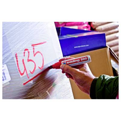 Écriture à la main « 435 » au marqueur rouge sur une boîte emballée dans du plastique dans une zone de stockage.