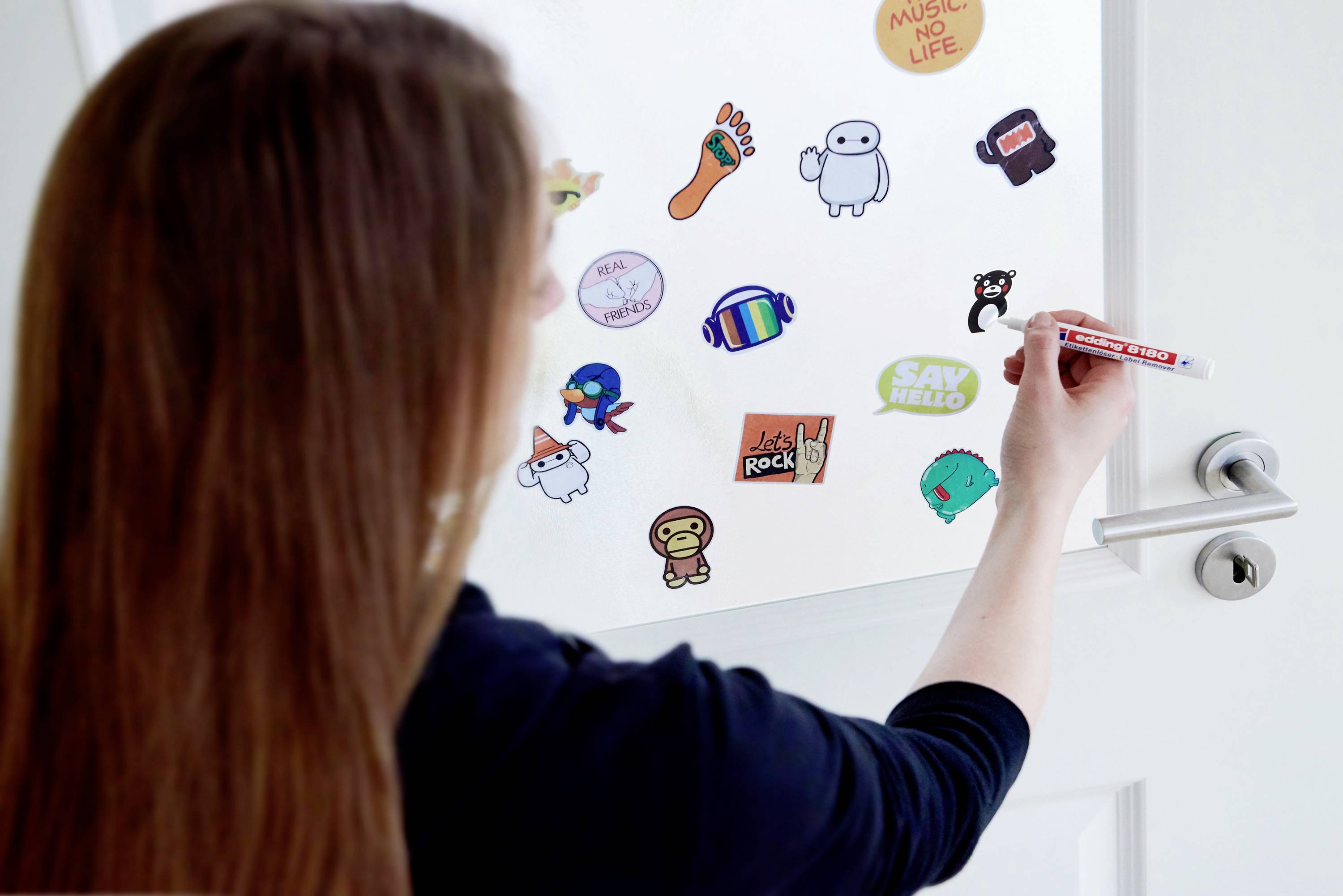 Une personne colle des autocollants colorés sur une porte tout en prenant des notes avec un stylo.