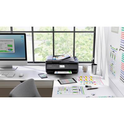 Une imprimante moderne sur un bureau imprime des diagrammes et des rapports en couleur. À côté se trouvent un écran d'ordinateur et des articles de bureau.