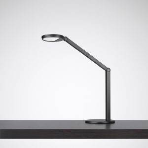Une lampe de table moderne en noir avec un bras articulé est posée sur une table sombre.