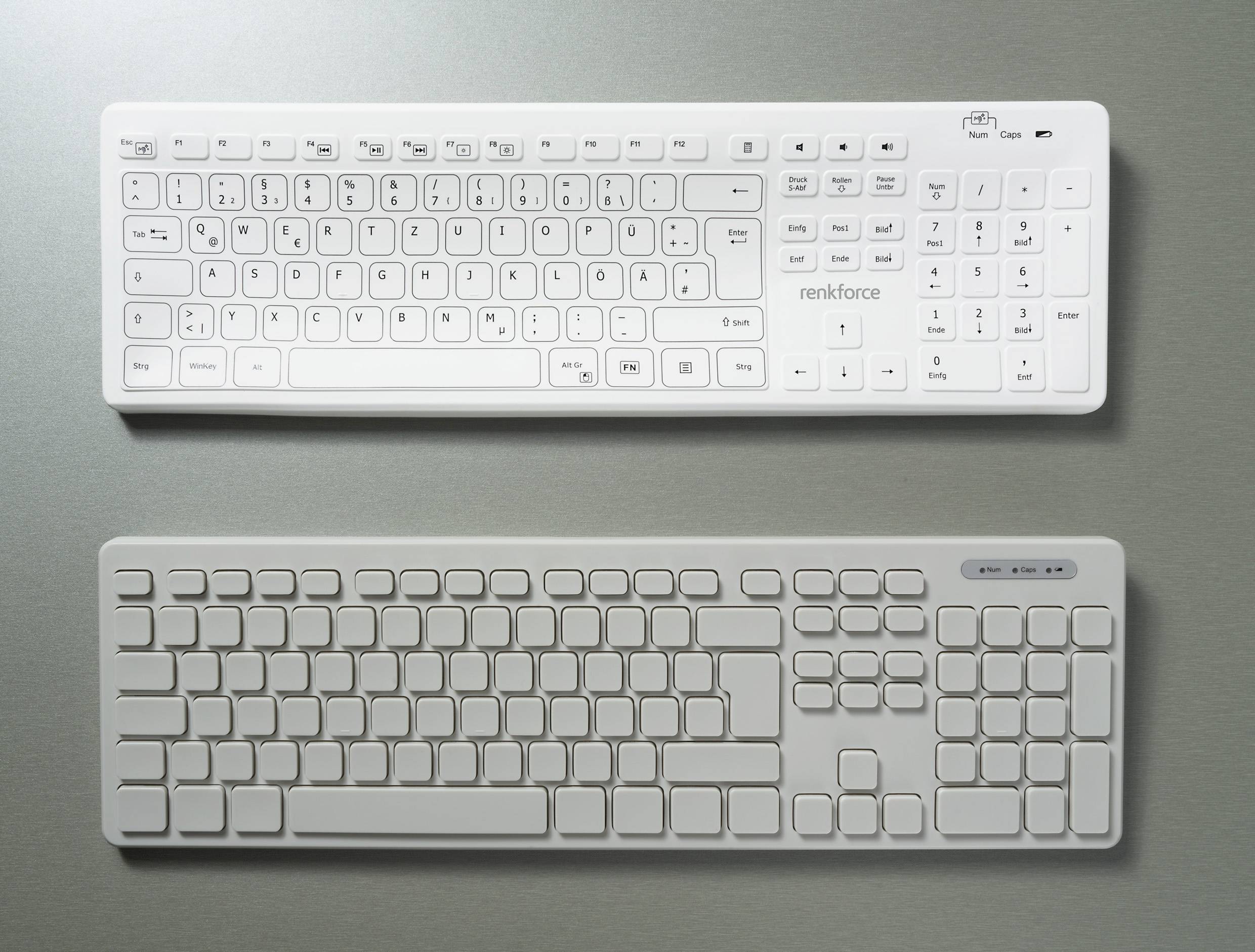 Deux claviers blancs sur un fond gris ; celui du haut avec des touches marquées en noir, celui du bas simple et uni sans inscriptions.