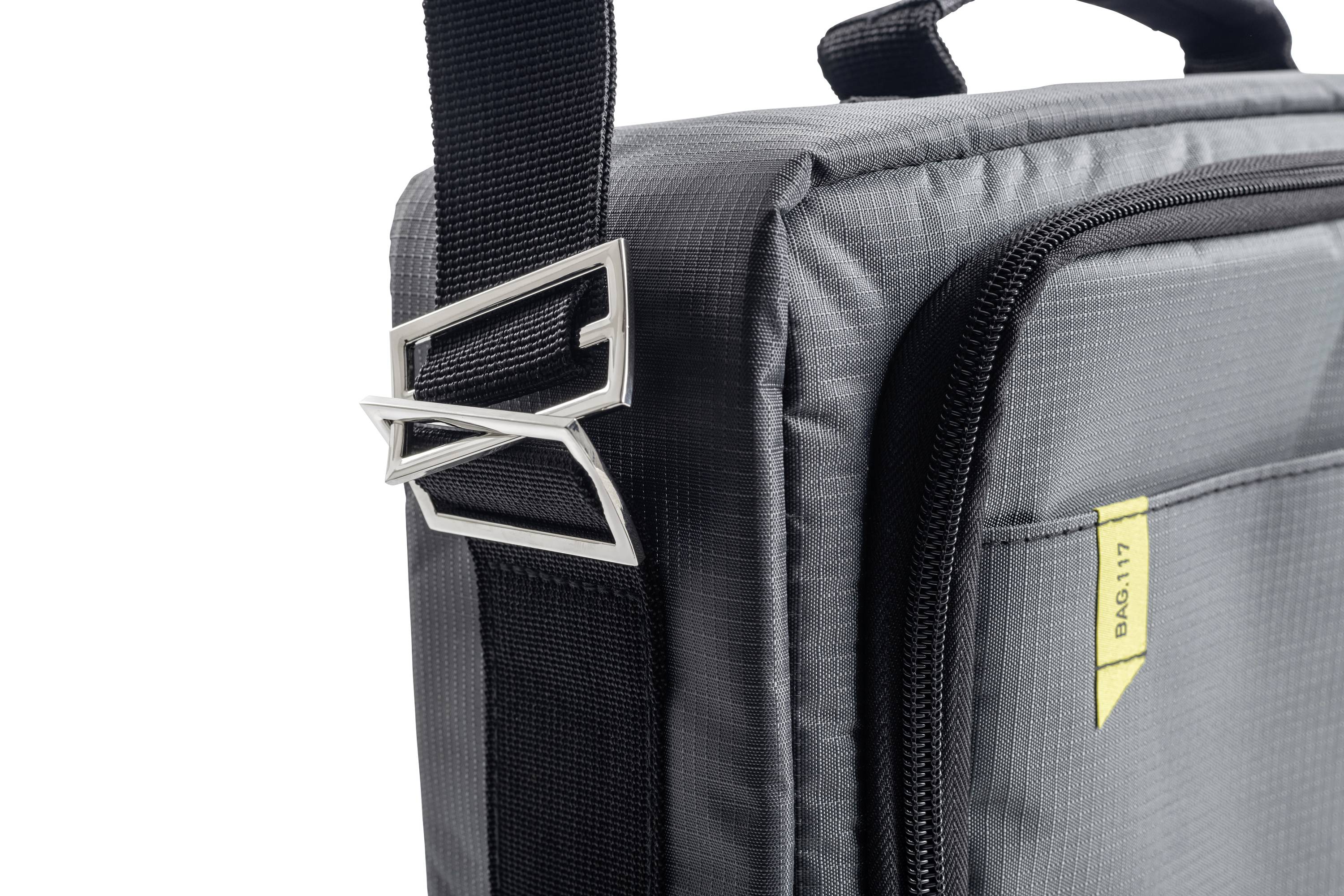 Un sac à bandoulière gris avec une bandoulière réglable et une poche à fermeture éclair. Une étiquette jaune porte l'inscription 'BAG-017'.