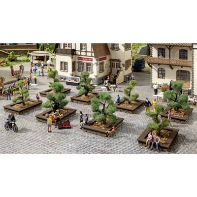 Scène de train miniature avec une place de village, des parterres de fleurs plantés et des personnages qui se promènent, sont assis ou conversent. En arrière-plan, des maisons à colombages.
