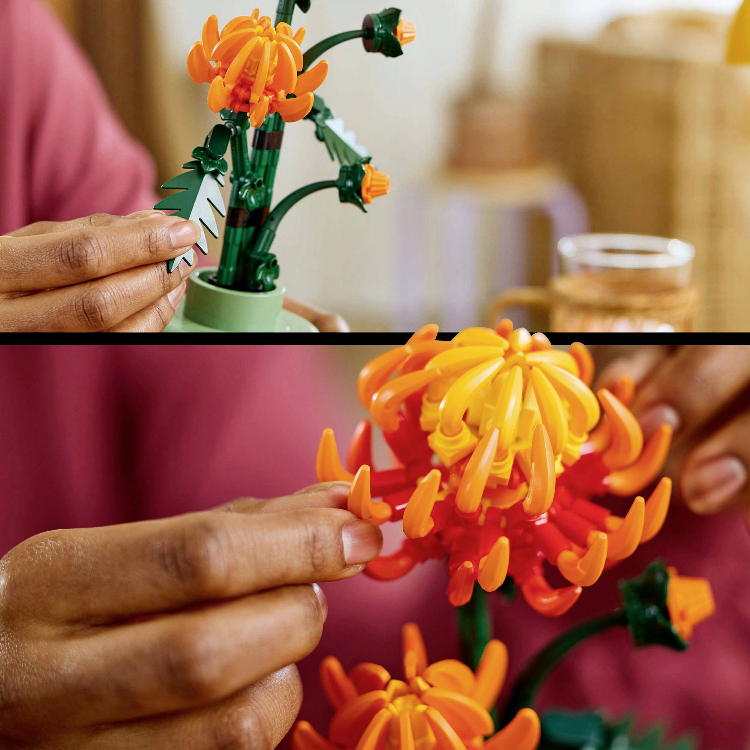 Une personne construit une fleur orange avec des briques LEGO. Les mains assemblent les pétales sur la tige.