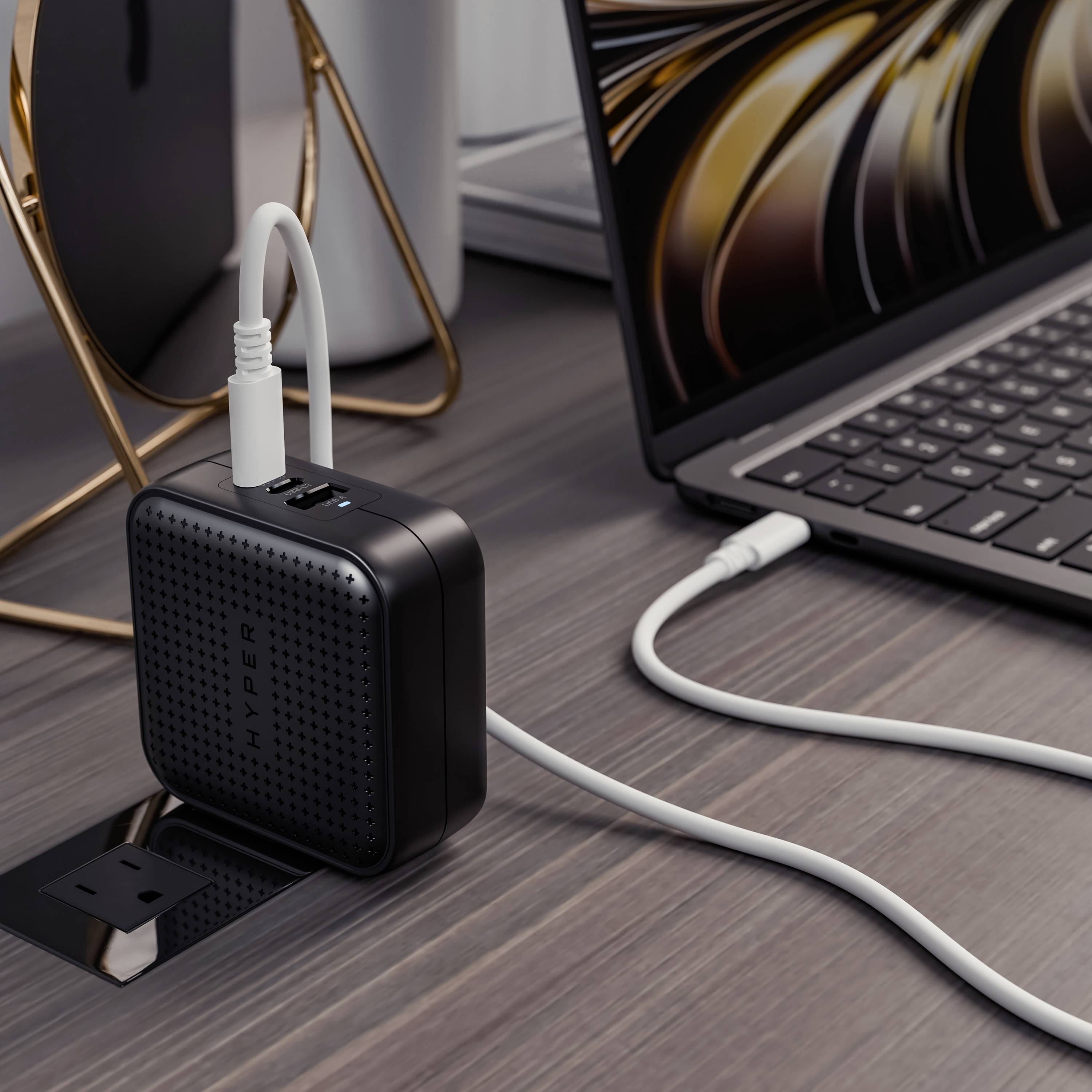 Un ordinateur portable est branché à une multiprise avec des ports USB, posée sur une table à côté d'un smartphone.