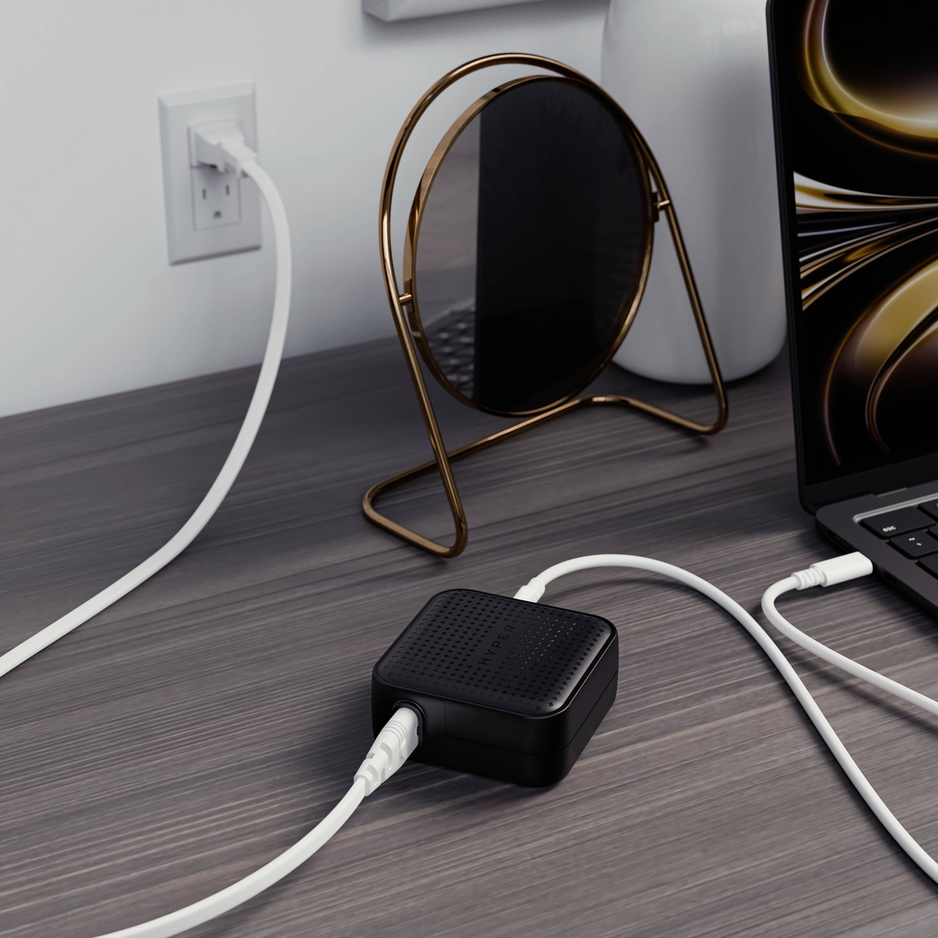 Un bureau moderne avec un ordinateur portable, un chargeur branché à une prise électrique, et des éléments décoratifs en arrière-plan.
