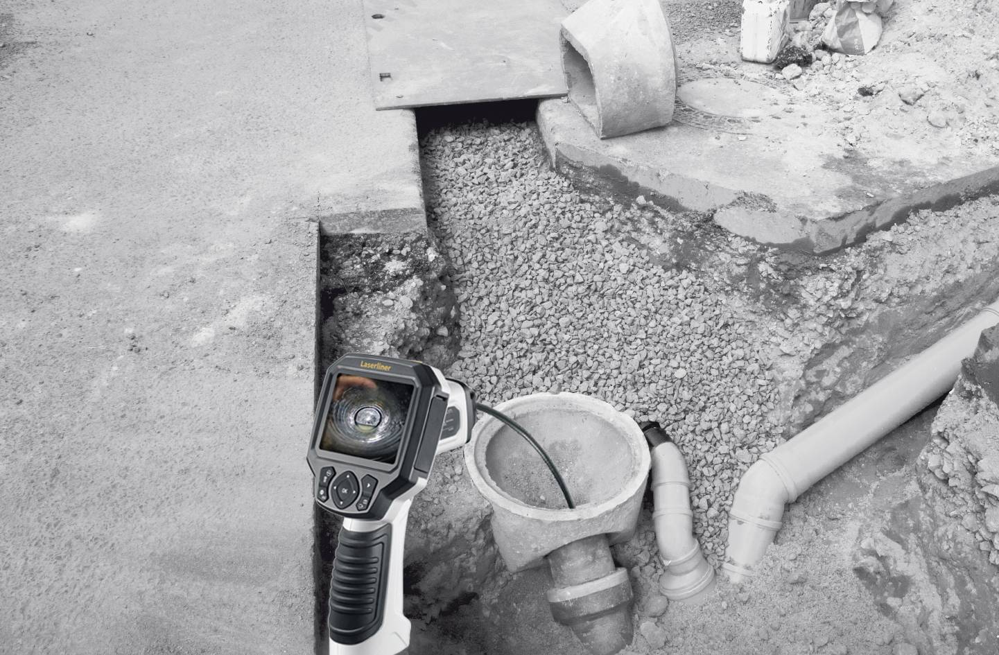 Un dispositif d'inspection qui se déplace dans un tuyau affiche une image sur son écran. Il est utilisé dans un chantier de construction routière et de canalisations.